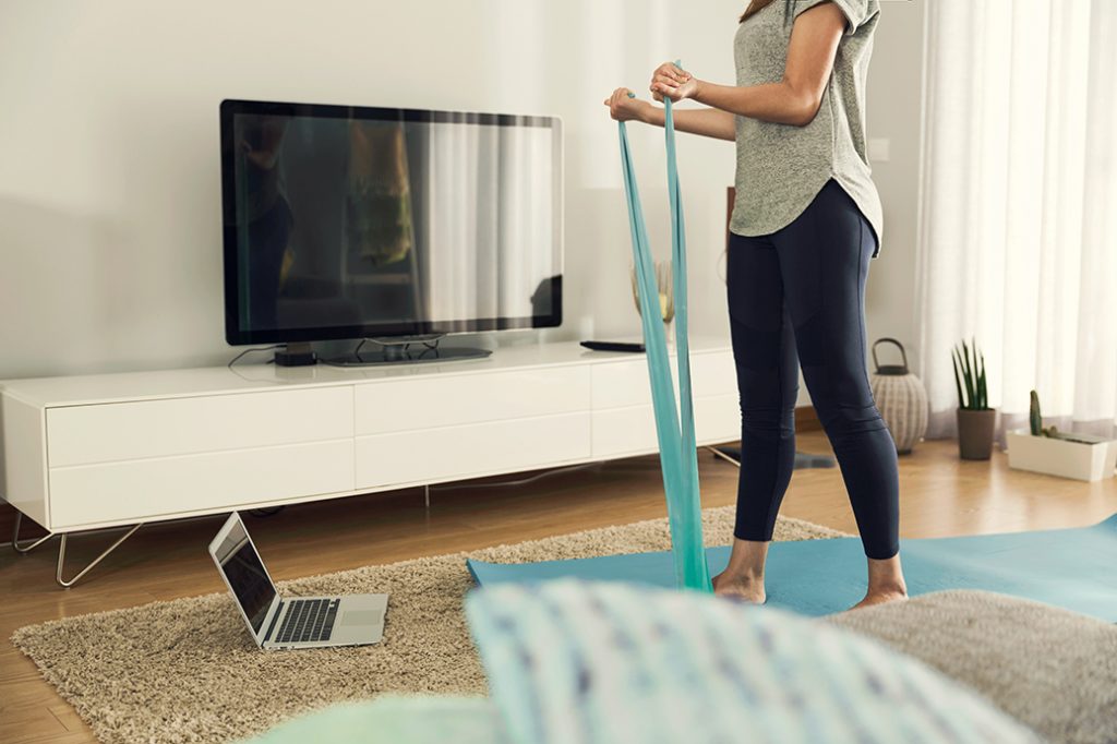woman using exercise band infront of laptop