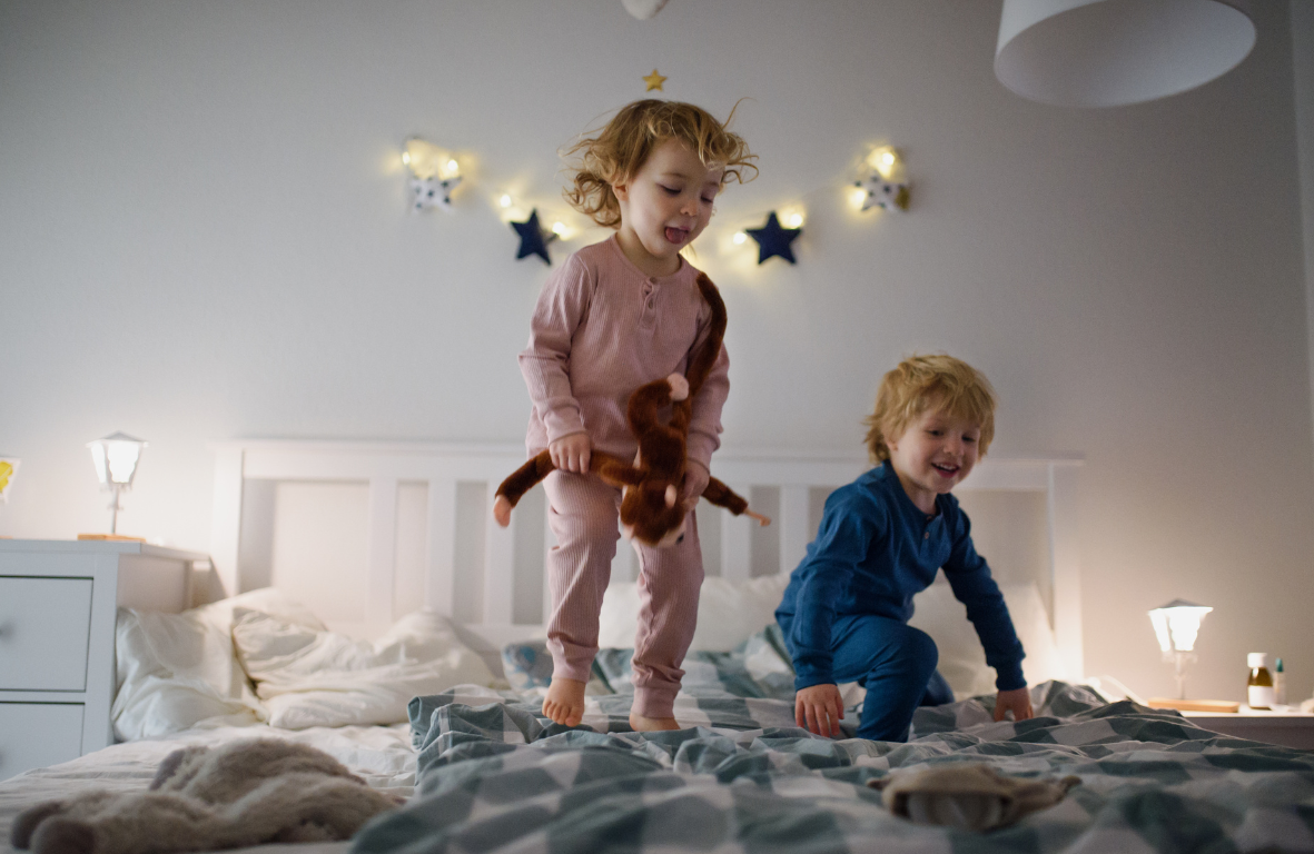 Boy and Girl preschoolers bouncing on a bed